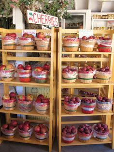 two wooden shelves filled with lots of different types of pies and fruit on them