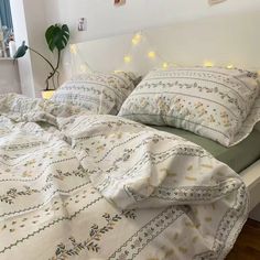 a white bed topped with lots of pillows next to a night stand filled with lights