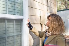 a woman with long hair is looking out the window at something on the side of her house