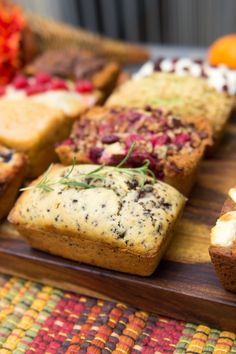 a wooden tray topped with lots of different types of cakes and muffins on top of each other