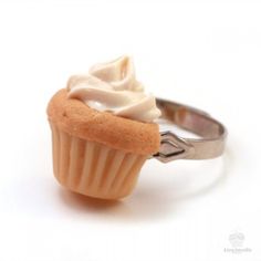 a small cupcake with white frosting on it's top sitting on a silver ring