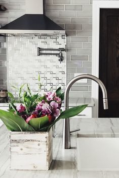 a white sink sitting under a faucet next to a wooden box filled with flowers