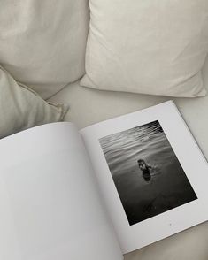 an open book sitting on top of a white couch next to pillows and pillow cases