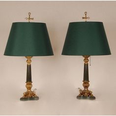 two green lamps sitting next to each other on top of a white table with gold trim