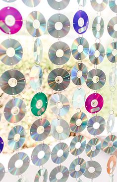 several cds are hanging from the ceiling in front of a window with curtains made out of them