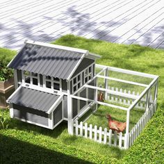 a chicken coop in the shape of a house with two chickens inside and one laying on the grass