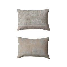 two pillows sitting next to each other on top of a white surface with blue and beige designs