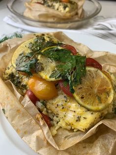 an omelet with tomatoes, spinach and other vegetables on it sitting on a plate