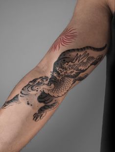 a man's arm with a dragon tattoo on the left side of his arm