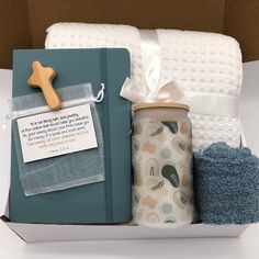 a gift box containing a baby's first book, mitt and blanket with a wooden cross on it