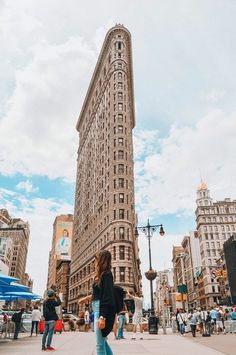 a woman walking down the street in front of a tall building with lots of windows