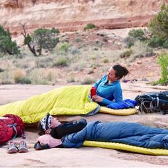 two people laying on the ground with sleeping bags