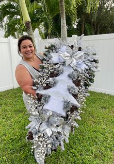 a woman is holding a christmas wreath in the grass with pine cones and snowflakes on it