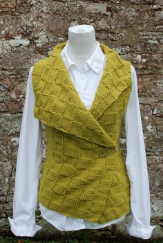 a woman's sweater vest on display in front of a brick wall