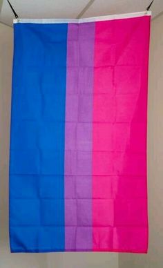 a pink, blue and purple flag hanging from a ceiling in a room with white walls