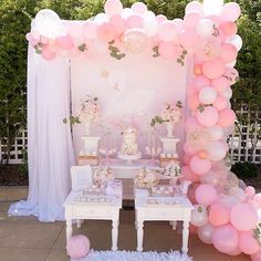 a table topped with lots of pink balloons next to a white cake and cupcakes