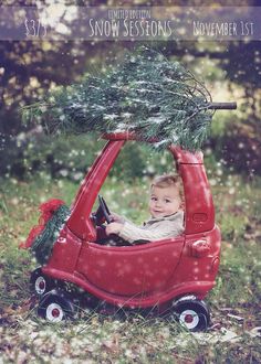 a little boy driving a red car with a christmas tree on the roof and steering wheel