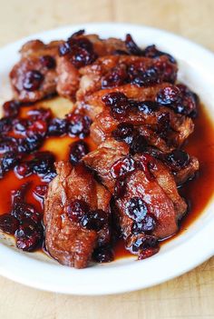 meat with cranberry sauce in a white bowl on a wooden table top,