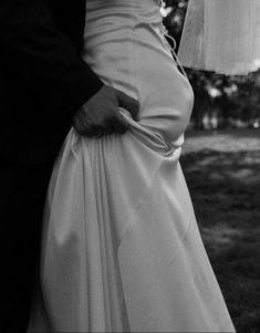 the bride and groom are standing under an umbrella in their wedding day attire, holding each other's hands