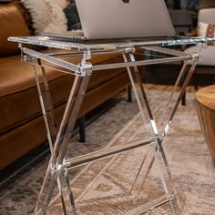 a laptop computer sitting on top of a glass table in front of a brown couch