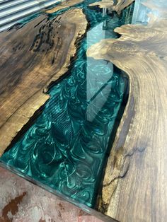 the table is made out of wood and has green glass on each side, along with a river running through it