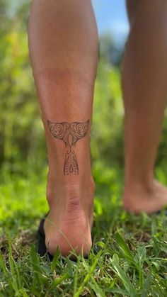 a person with a tattoo on their foot walking in the grass, wearing sandals and flip flops