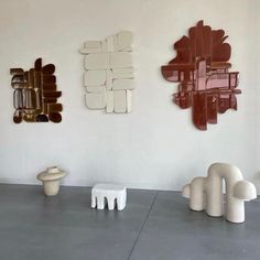 three abstract sculptures are displayed on the wall