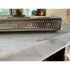 a silver tray sitting on top of a marble counter next to a mirror and lamp