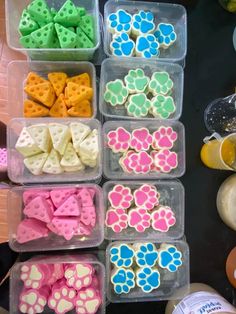 several plastic containers filled with different colored dog paw shaped treats