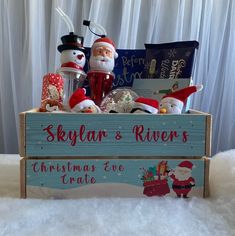 a wooden box filled with christmas items on top of a white bed covered in snow