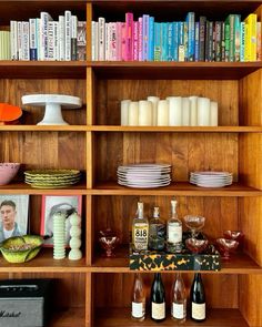 a book shelf filled with lots of books and wine bottles on top of wooden shelves