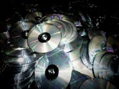 many cds are stacked on top of each other in this dark room with light shining through them