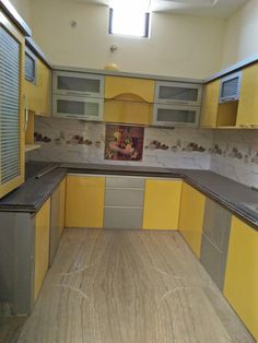 an empty kitchen with yellow and gray cabinets