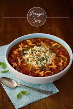 a white bowl filled with pasta and sauce on top of a blue napkin next to a spoon