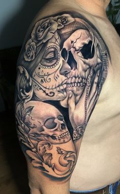 a man's half sleeve with skulls and roses on the arm, in black and grey