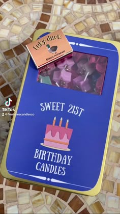 a birthday card with candles on it sitting on a mosaic tile table top in the shape of a cake