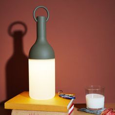 a bottle sitting on top of a table next to a glass of milk and some books