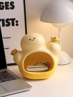 a laptop computer sitting on top of a desk next to a yellow bird shaped object