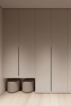 an empty room with three round stools in the corner and several cupboards behind it