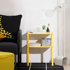 a living room with a yellow table next to a black chair and white wall in the background