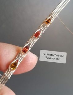 a person is holding an orange and yellow beaded bracelet with silver wire on it