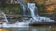 the waterfall is surrounded by large rocks and water