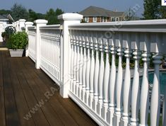 a wooden deck with white railings next to a swimming pool