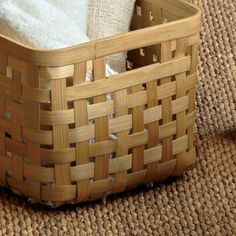 a basket with towels in it sitting on the floor next to a toilet paper roll