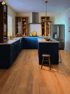 a large kitchen with blue cabinets and wooden flooring, along with a bar stool