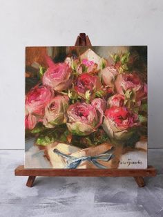 an easel holding a painting of pink roses