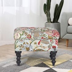 an upholstered footstool sits in front of a potted cactus