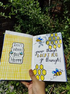 a hand holding an open notebook with bees on it and the words don't worry bee happy