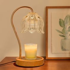 a glass candle sitting on top of a wooden table next to a framed photograph and a painting