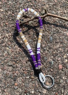 a purple and white beaded lanyard with a pair of scissors on the ground